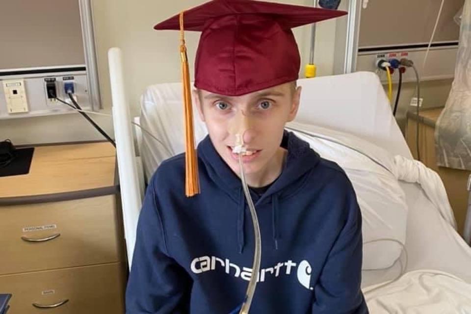 Eric poses in hospital with a graduation cap. He graduated high school early and later perused his goal of becoming a heavy duty mechanic by starting his level 1 apprenticeship in college (GoFundMe)