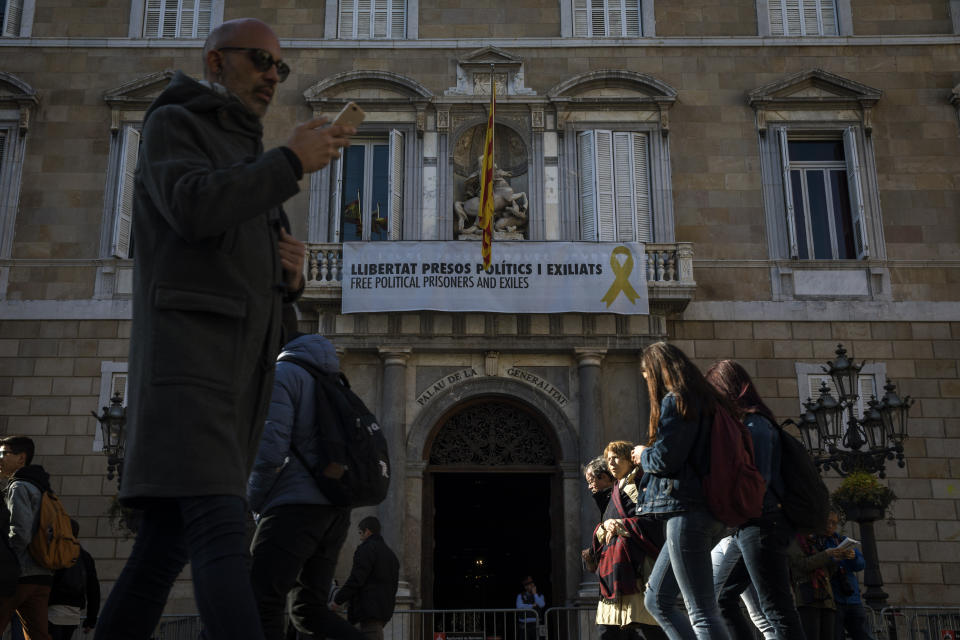 A banner reading "Free Political Prisoners and Exiles", with a yellow ribbon, hangs at the headquarter of the Government and the Presidency of Catalonia in Barcelona, Spain, Wednesday, March 20, 2019. A dispute between Spanish authorities and Catalan separatists over a yellow ribbon symbol is building into a hot issue ahead of Spain's general election next month. (AP Photo/Emilio Morenatti)