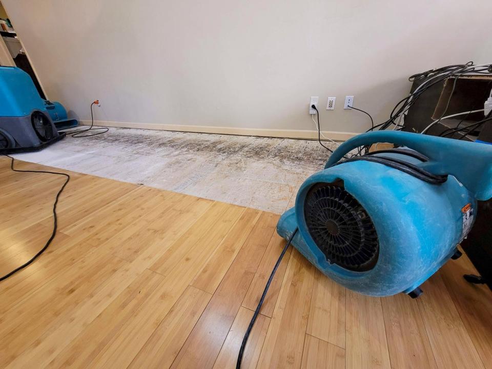 Blue dehumidifiers dry out a section of floor that has water damage.