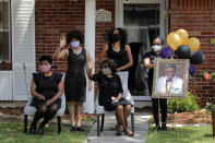 The family of Larry Hammond wave as a line of cars with friends and family, who could not attend his funeral because of limits of gatherings of more than 10 people, due to the coronavirus pandemic, pass by their home, in New Orleans, April 22, 2020. (AP Photo/Gerald Herbert)