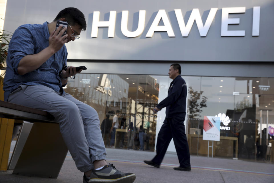 A man uses two smartphones at once outside a Huawei store in Beijing Monday, May 20, 2019. Google is assuring users of Huawei smartphones the American company's services still will work on them following U.S. government restrictions on doing business with the Chinese tech giant. (AP Photo/Ng Han Guan)