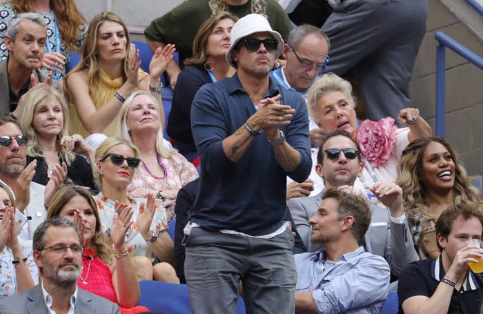 Brad in sunglasses, standing and applauding, with Laverne Cox in the row behind him on the right