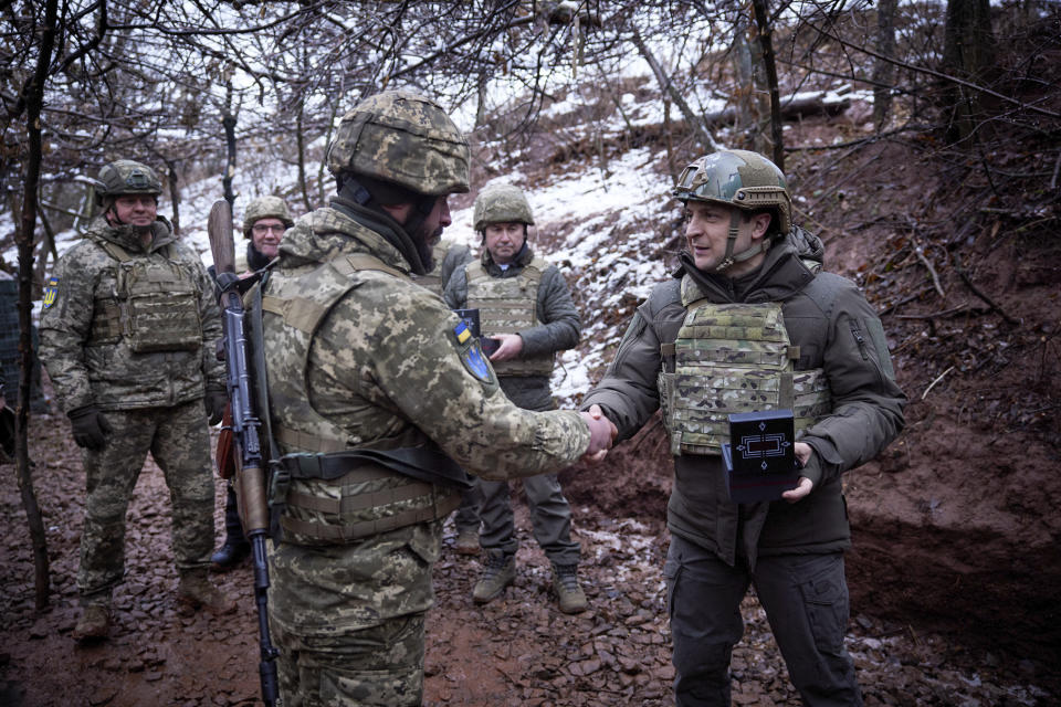 Ukrainian President Volodymyr Zelenskyy, right, awards a soldier in a trench as he visits the war-hit Donetsk region, eastern Ukraine, Monday, Dec. 6, 2021. (Ukrainian Presidential Press Office via AP)