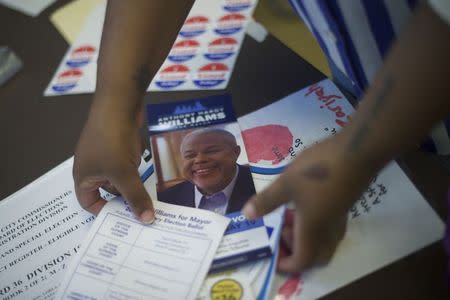 A woman collects brochures on Philadelphia mayoral candidate Tony Williams inside a voting station on primary election day in Philadelphia, Pennsylvania on May 19, 2015. REUTERS/Mark Makela