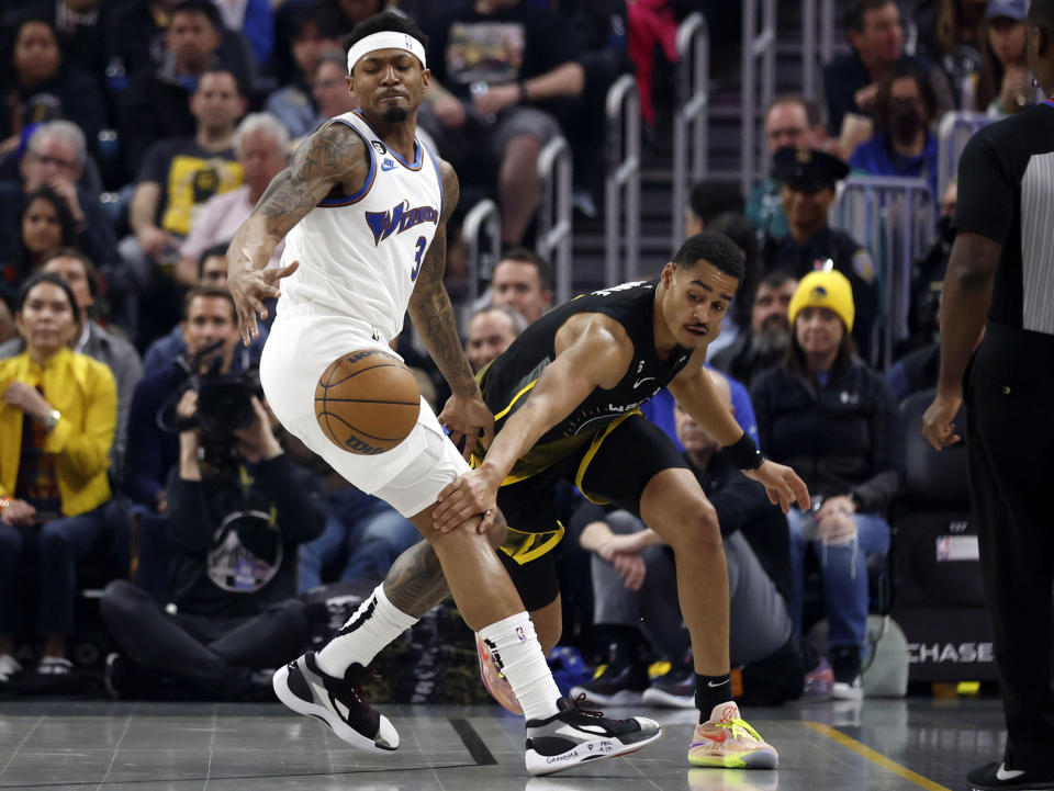 Golden State Warriors guard Jordan Poole, right, reaches for the ball against Washington Wizards guard Bradley Beal, left, during the first half of an NBA basketball game in San Francisco, Monday, Feb. 13, 2023. (AP Photo/Jed Jacobsohn)