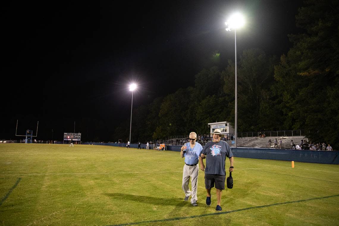 Hayden Shackelford (right) jokes with Tom Husketh (left) as they leave the field after a home game at South Granville High School. For more than 20 years, the two men have attended South Granville’s football games, and Shackelford’s descriptive commentary helps Husketh, who is blind, “see” the game.