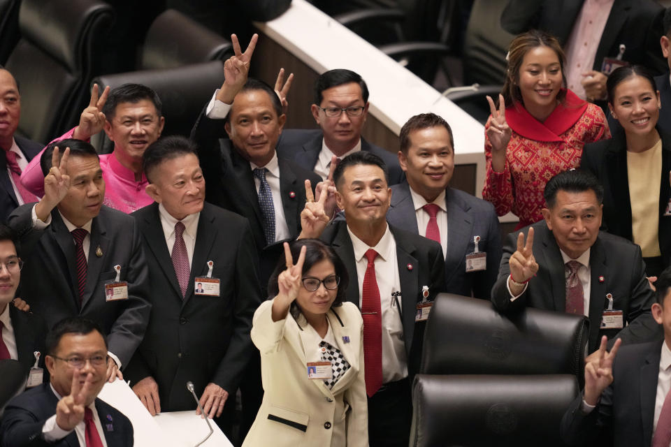 Leader of Pheu Thai party Chonlanan Srikaew, center, and his party lawmakers make victory signs at Parliament in Bangkok, Thailand, Tuesday, Aug. 22, 2023, after securing enough votes in parliament for their nominee Srettha Thavisin to become Thailand's 30th prime minister. (AP Photo/Sakchai Lalit)