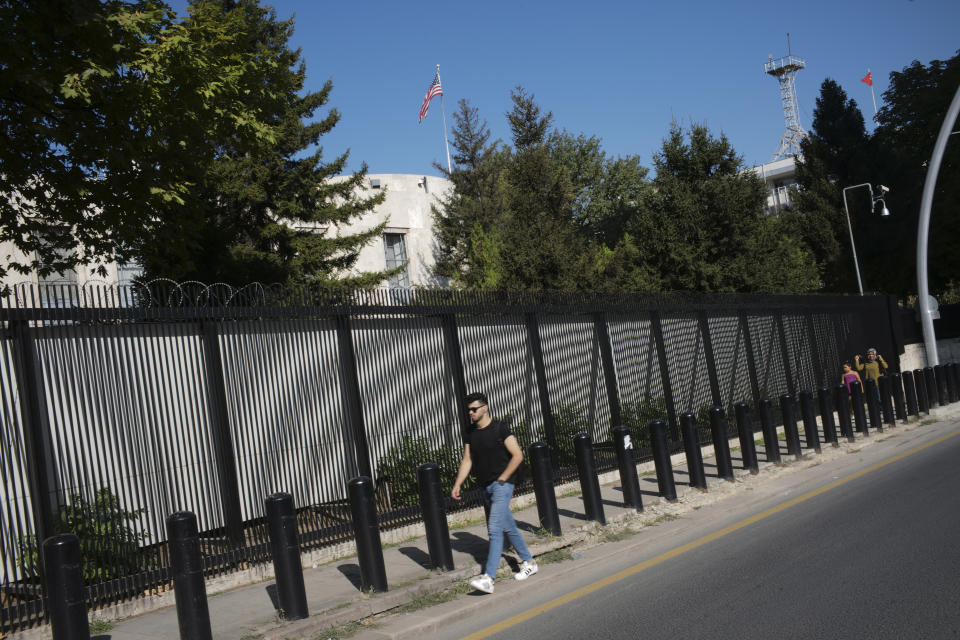 People walk outside the U.S. Embassy in Ankara, Turkey, Monday, Aug. 20, 2018. Shots were fired at a security booth outside the embassy in Turkey's capital early Monday, but U.S. officials said no one was hurt. Ties between Ankara and Washington have been strained over the case of an imprisoned American pastor, leading the U.S. to impose sanctions, and increased tariffs that sent the Turkish lira tumbling last week. (AP Photo/Burhan Ozbilici)