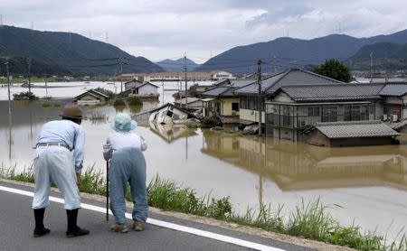 FILE PHOTO: An elderly couple looks at a flooded area after heavy rain in Kurashiki, Okayama Prefecture, Japan, in this photo taken by Kyodo July 8, 2018. Mandatory credit Kyodo/via REUTERS/File Photo