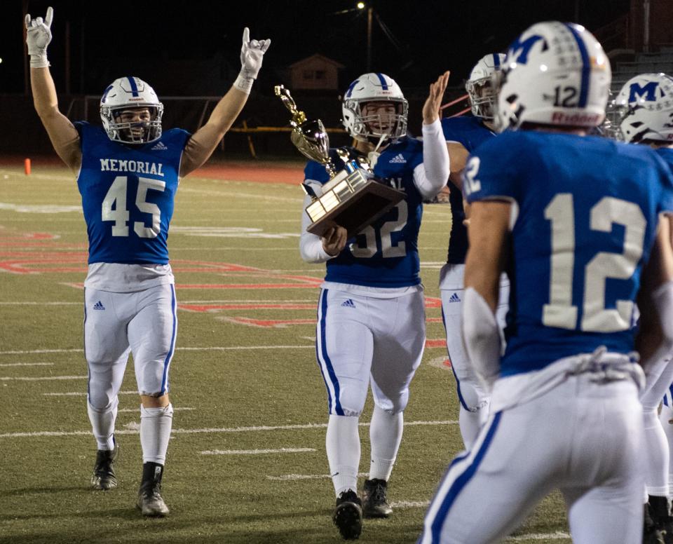 Memorial Tigers players celebrate with the Cake Eaters trophy after a victory against the Castle Knights at Enlow Field in Evansville, Ind., Friday evening, Oct. 14, 2022. 