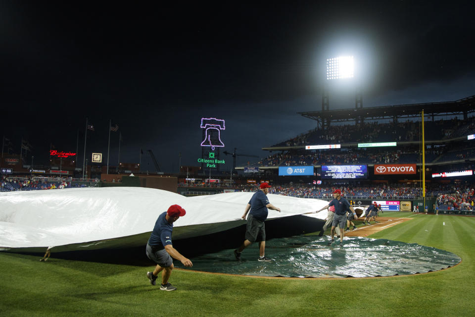 Workers cover the infield as inclement weather delays a baseball game between the Philadelphia Phillies and the Los Angeles Dodgers, Wednesday, July 17, 2019, in Philadelphia. (AP Photo/Matt Slocum)