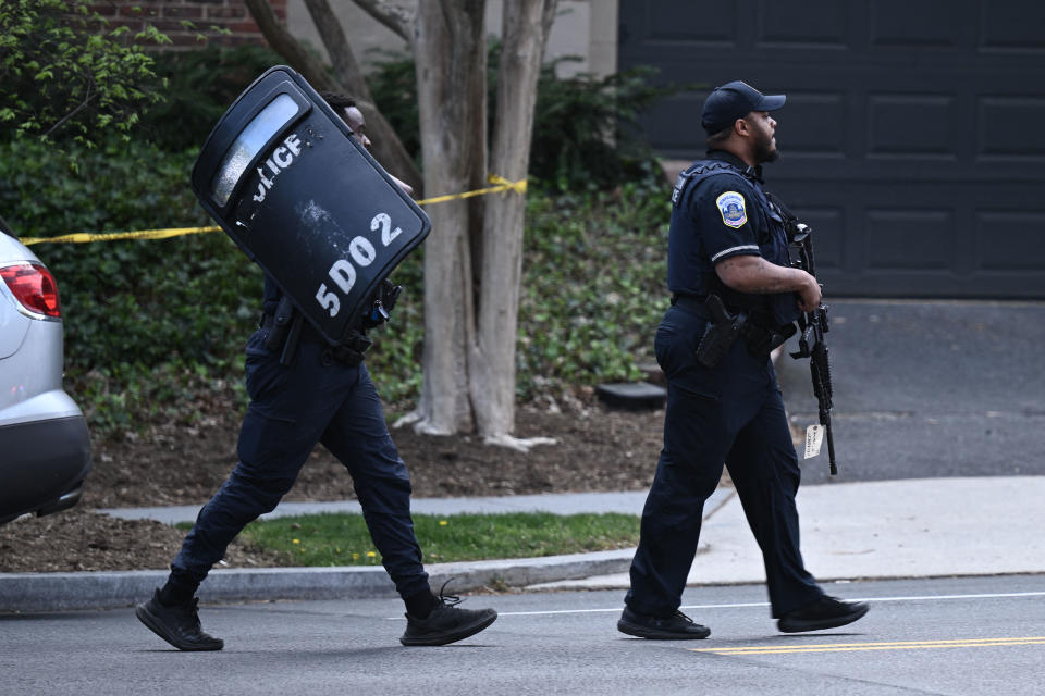 Police officers with rifles and ballistic shields respond to an alleged shooting 