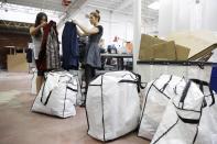 In this photo taken Wednesday, April 9, 2014, Mayola Martinez, a men's category director, left, and Samantha Emley, a luxury coordinator, examine men's suits by Etro and Kiton that arrived for consignment at the headquarters of The RealReal in San Francisco. The suits and bags in the foreground were all picked up from one man putting his clothing on consignment. An explosion of resale online sites from RealReal to Chairish that allows shoppers to easily trade in their gently used top brand handbags, furniture and gadgets for cash is changing the way Americans buy. (AP Photo/Eric Risberg)