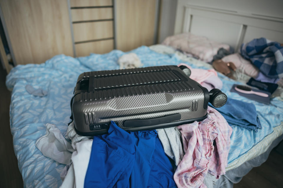 A chaotic scene of piles of clothes and luggage.