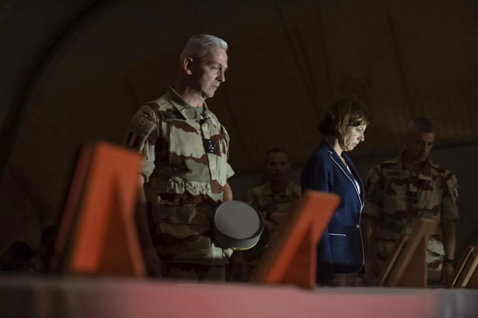 In this Wednesday, Nov. 27, 2019, photo provided by French Defense Communication and Audiovisual Department (ECPAD), French Defense Minister Florence Parly, right, and French Army Chief of Staff Gen. Francois Lecointre, pay their respects to the 13 French soldiers, in Gao, Mali. Parly arrived in northern Mali on Wednesday after a helicopter collision killed 13 French soldiers fighting Islamic State group-linked extremists, while some in the West African country debated France’s military presence. (Thomas Peudeleux/ECPAD via AP)