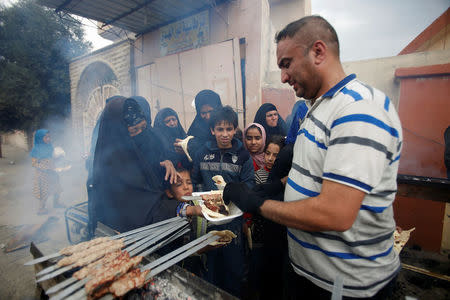 An Iraqi volunteer (R) gives food to displaced people during a battle with Islamic State militants in Mosul, Iraq March 28, 2017. REUTERS/Khalid al Mousily