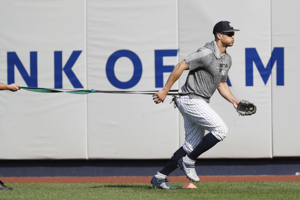 New York Yankees' Giancarlo Stanton, who has been out the much of the season with various injuries, trains with a resistance band in the outfield before a baseball game between the Yankees and the Texas Rangers, Wednesday, Sept. 4, 2019, in New York. (AP Photo/Kathy Willens)