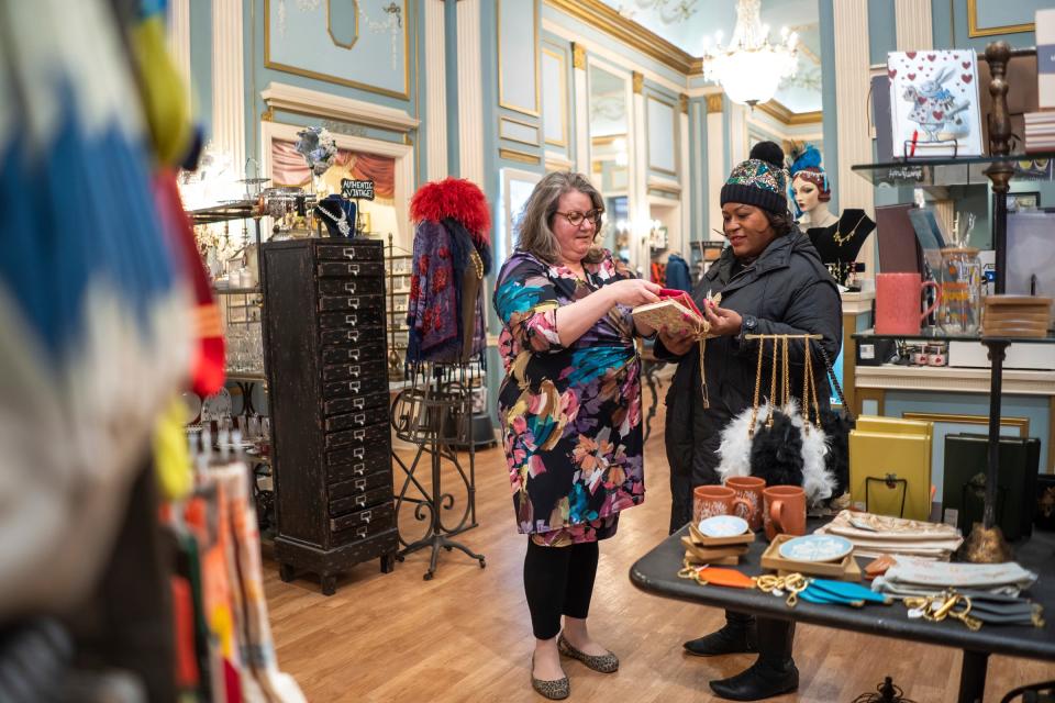 The Peacock Room proprietress Rachel Lutz, left, talks with Lesley Esters Redwine of Detroit while showing her the features on an item at her business located in the Fisher Building in Detroit on Wednesday, November 29, 2023.