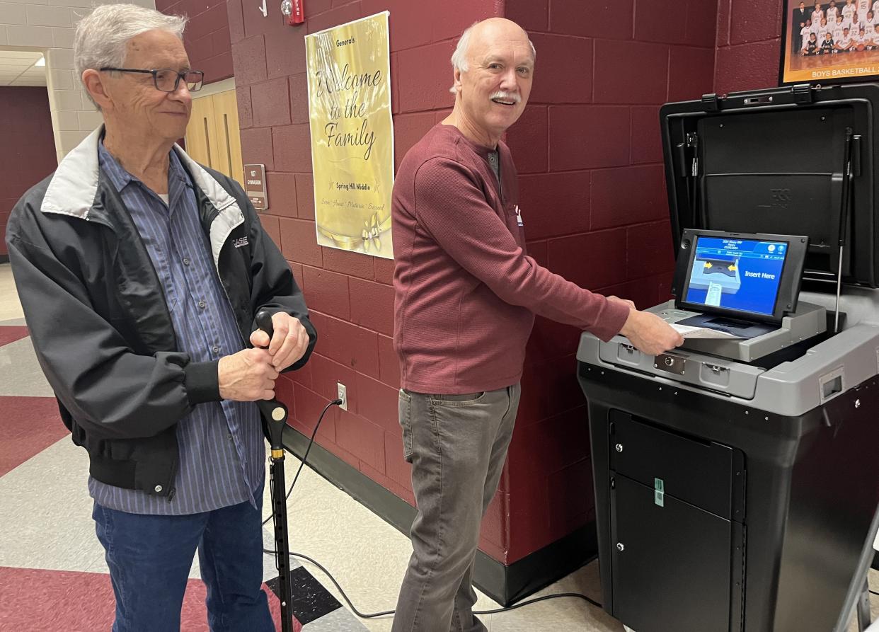Maury County voter Allen Janssen (left) of Spring Hill watches as Spring Hill Middle School polling officer slides his paper ballot into a tabulation machine after using an ink pen to bubble in his chosen candidates on March 5, 2024 in Columbia, Tenn.