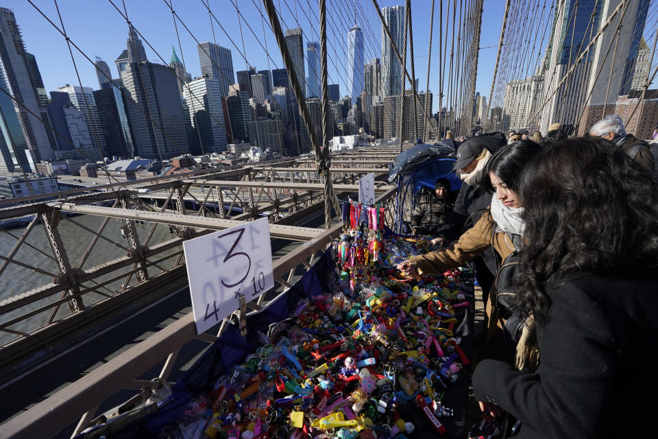 Pedestrians shop at vendors selling souvenirs on the Brooklyn Bridge in New York, Tuesday, Jan. 2, 2024. New York City will ban vendors from the Brooklyn Bridge starting Wednesday, Jan. 3, 2024. The move is intended to ease overcrowding on the famed East River crossing, where dozens of souvenir sellers currently compete for space with tourists and city commuters. (AP Photo/Seth Wenig)