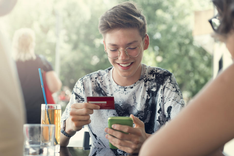 Teenager Boy and her friends Use credit card for shopping online in the cafeteria