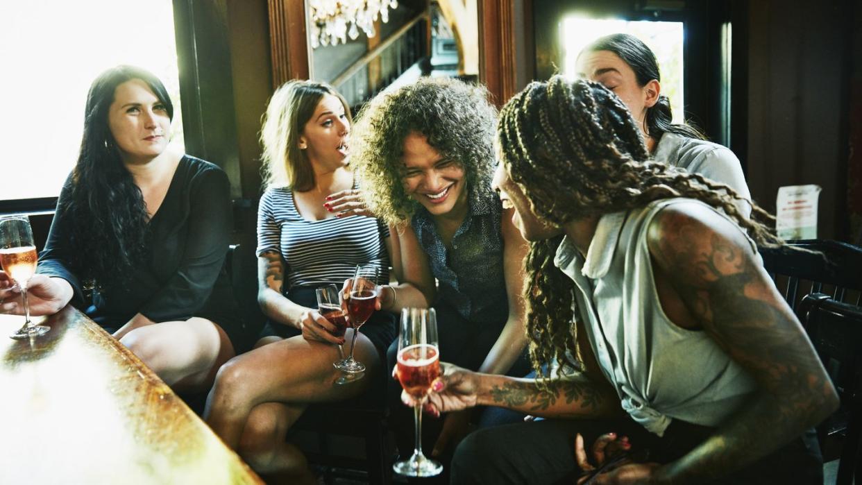 laughing group of female friends hanging out in bar