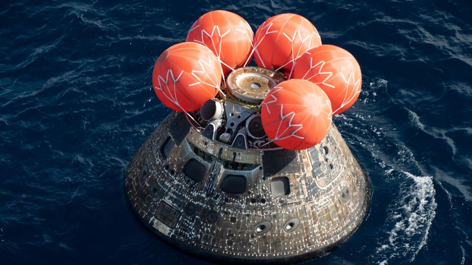 A gray space capsule floats in the ocean