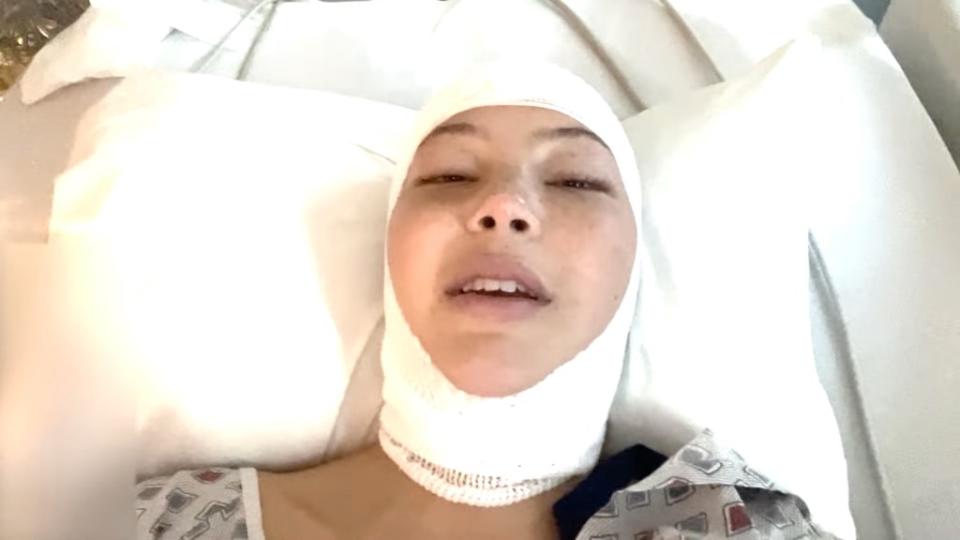 Following the explanation, the vlog cuts to Strahan laying in her bed with several bandages wrapped tightly around her skull. Isabella Strahan/YouTube