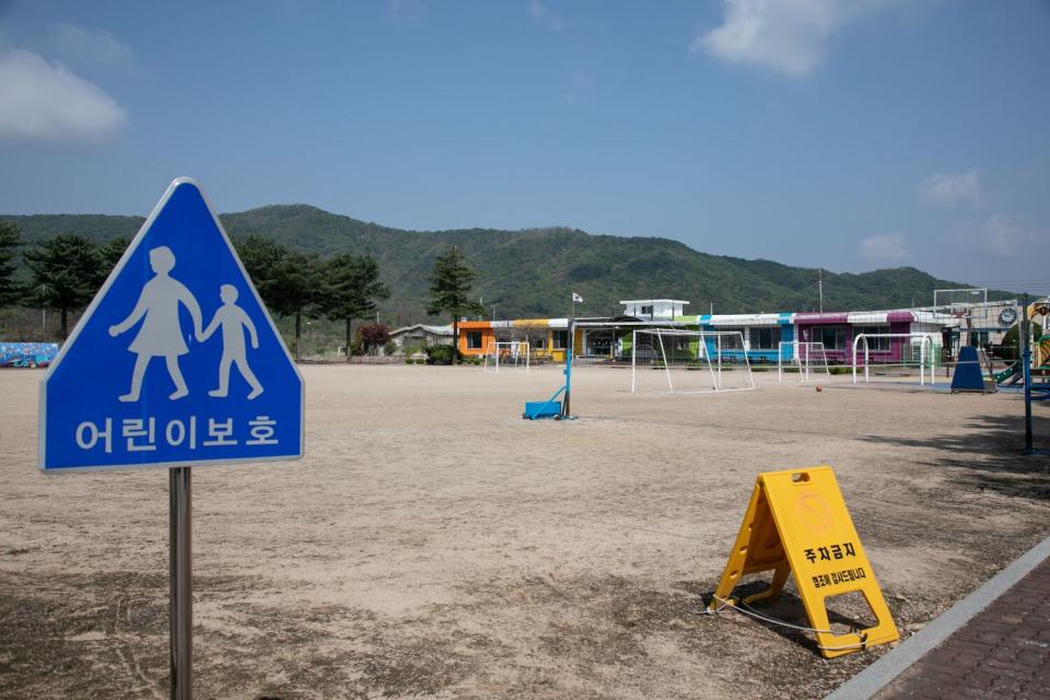 Signs say "Protect the Children," left, and "No Parking" at Dochang Elementary.