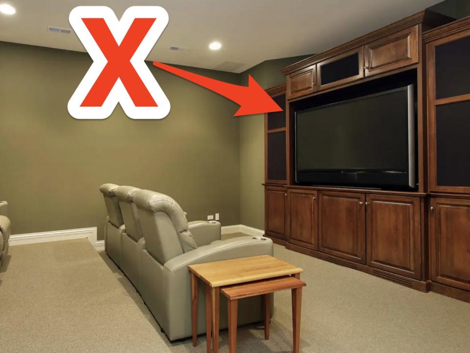 red x and arrow pointing at a large wooden entertainment center with a flat screen tv in a home theater