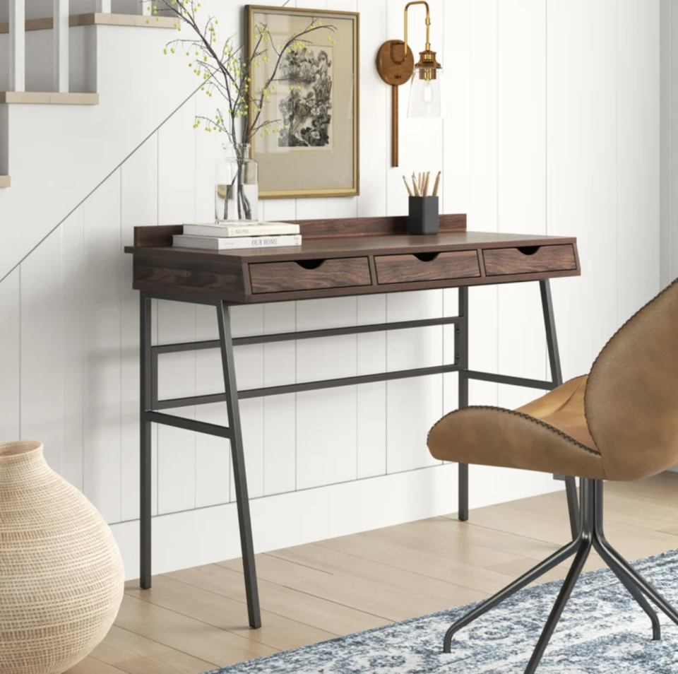 Sand &amp; Stable Canal Desk in brown wood against white staircase and brown chair (Photo via Wayfair)