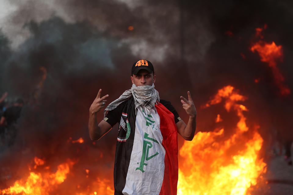 An anti-government protester flashes the victory sign during a demonstration, in Baghdad, Iraq, Thursday, Oct. 3, 2019. Iraqi security forces fired live bullets into the air and used tear gas against a few hundred protesters in central Baghdad on Thursday, hours after a curfew was announced in the Iraqi capital on the heels of two days of deadly violence that gripped the country amid anti-government protests that killed over 19 people in two days. (AP Photo/Hadi Mizban)