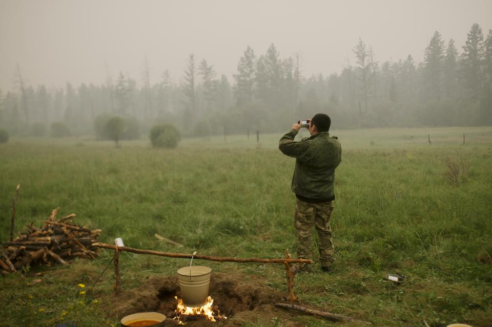 A member of volunteers crew monitors the fire from spreading at Gorny Ulus area west of Yakutsk, Russia, Tuesday, July 20, 2021. The hardest hit area is the Sakha Republic, also known as Yakutia, in the far northeast of Russia, about 5,000 kilometers (3,200 miles) from Moscow. Volunteers have joined over 5,000 regular firefighters in the effort, motivated by their love of the vast region. The volunteers rely on their own money or funds from nongovernmental groups. (AP Photo/Ivan Nikiforov)