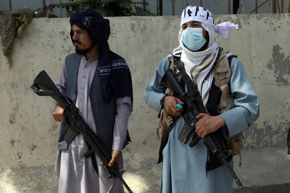 Taliban fighters stand guard in the main gate leading to Afghan presidential palace, in Kabul, Afghanistan, Monday, Aug. 16, 2021.