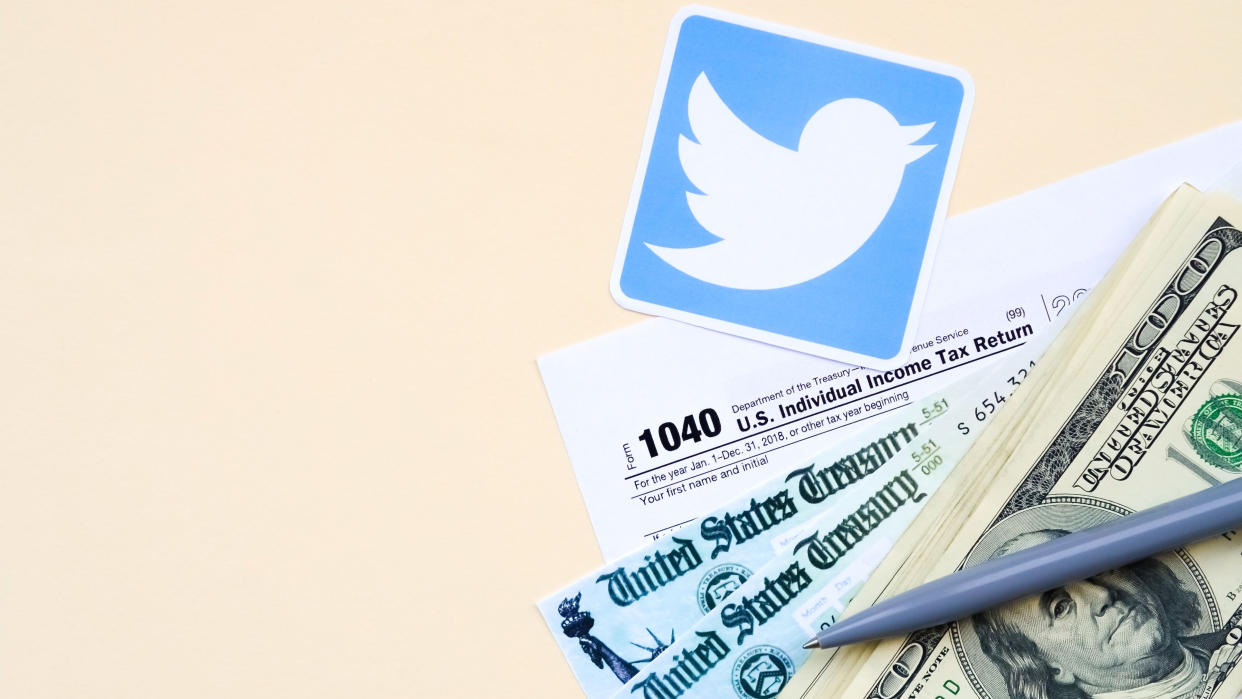  Twitter printed logo lies with 1040 Individual Income tax return form with Refund Check and hundred dollar bills on beige background. Help in tax period from social network concept 