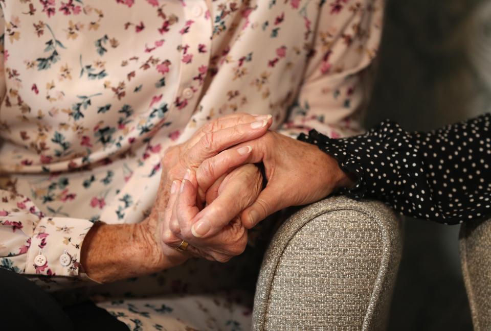 <p>A care home resident holds hands with her daughter </p> (PA)