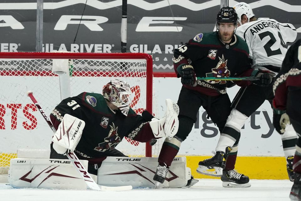 A shot by Los Angeles Kings' Gabriel Vilardi, not seen, slips past Arizona Coyotes goaltender Adin Hill (31) for a goal as Coyotes defenseman Jordan Oesterle (82) and Kings center Lias Andersson (24) work for position during the first period of an NHL hockey game Wednesday, May 5, 2021, in Glendale, Ariz. (AP Photo/Ross D. Franklin)