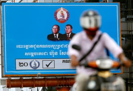 A man rides a motorcycle as a poster of the Cambodian People's Party (CPP) is seen at Koh Pich island in Phnom Penh, Cambodia, July 31, 2018. REUTERS/Samrang Pring