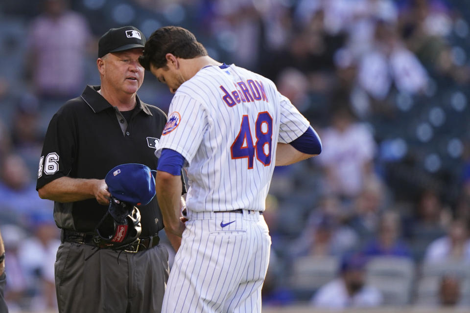 New York Mets starter Jacob deGrom (48) unbuckles his belt for third base umpire Ron Kulpa (46) after leaving the mound after pitching the top of the fifth inning of a baseball game against the Atlanta Braves, Monday, June 21, 2021, in New York. (AP Photo/Kathy Willens)