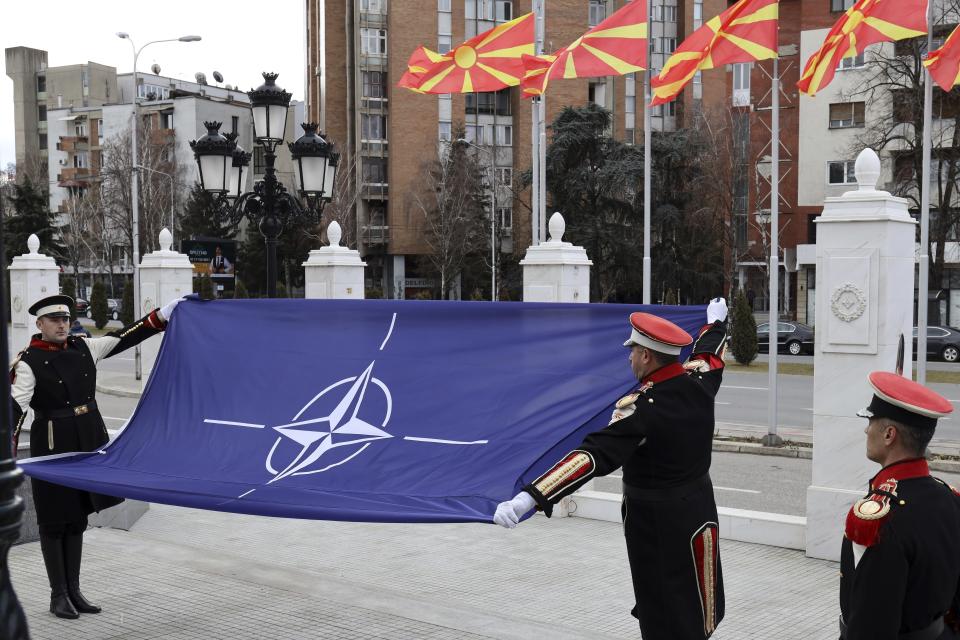 Macedonian soldiers raise the NATO flag in front of the government building during a ceremony in Skopje, Tuesday, Feb. 12, 2019. Macedonian authorities began removing official signs from government buildings to prepare for the country's new name: North Macedonia. (AP Photo/Dragan Perkovksi)