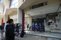 People pray for victims of Saturday's soccer match stampede in front of gate 13 the Kanjuruhan Stadium in Malang, Indonesia, Tuesday, Oct. 4, 2022. Indonesian police said Tuesday that the gates at the soccer stadium where police fired tear gas and set off a deadly crush were too small and could only accommodate two at a time when hundreds were trying to escape. (AP Photo/Achmad Ibrahim)