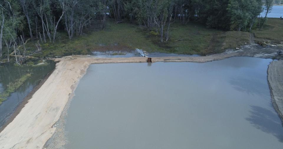 Water carries sediment into a forested area of the Mississippi River backwaters near the Wisconsin-Iowa border. The technique, called thin layer placement, is meant to raise the forest floor by a few inches and protect trees from flooding.