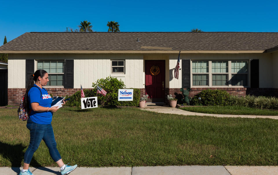 Arleen Sevilla walks by a house with signs supporting Sen. Bill Nelson (D-Fla.) while canvassing in Orlando. (Photo: Chris McGonigal/HuffPost)