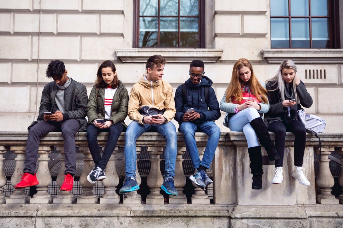 Teenagers sitting on a wall  (Getty)