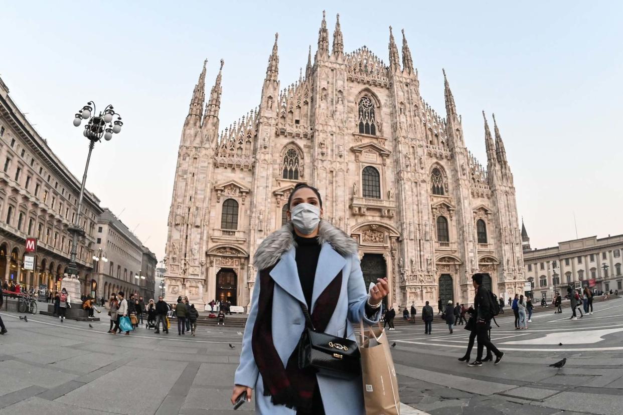 A woman with a protective face mask in front of the Duomo in Milan: AFP via Getty Images