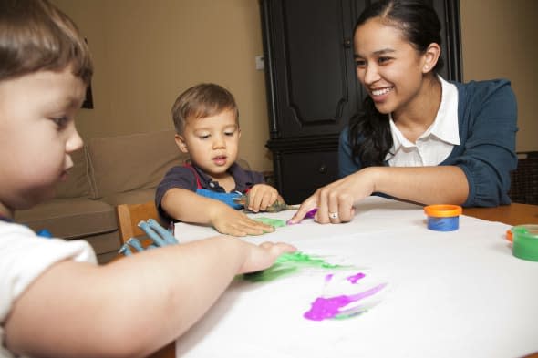 Childcare Worker Helping Two Young Boys with Fingerpaint.See more of this series: