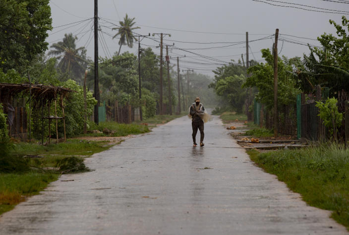 A man walks on the road to Playa Cajio, which has been cut off by the storm surge of Hurricane Ian, in Artemisa, Cuba, Tuesday, September 27, 2022. Ian made landfall at 4:30 a.m. EDT Tuesday in Cuba's Pinar del Rio province, where officials set up shelters, evacuated people, rushed in emergency personnel and took steps to protect crops in the nation's main tobacco-growing region. (AP Photo/Ismael Francisco)