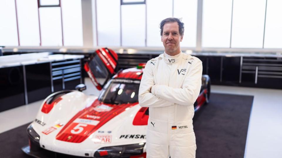 a man in a white suit standing next to a race car