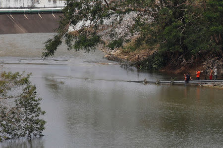 People look at the water flowing over the road at the dam of the Guajataca lake. REUTERS/Carlos Garcia Rawlins