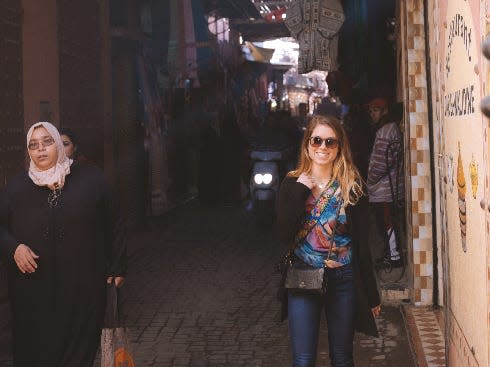 A woman standing in a street wearing jeans and a t shirt.